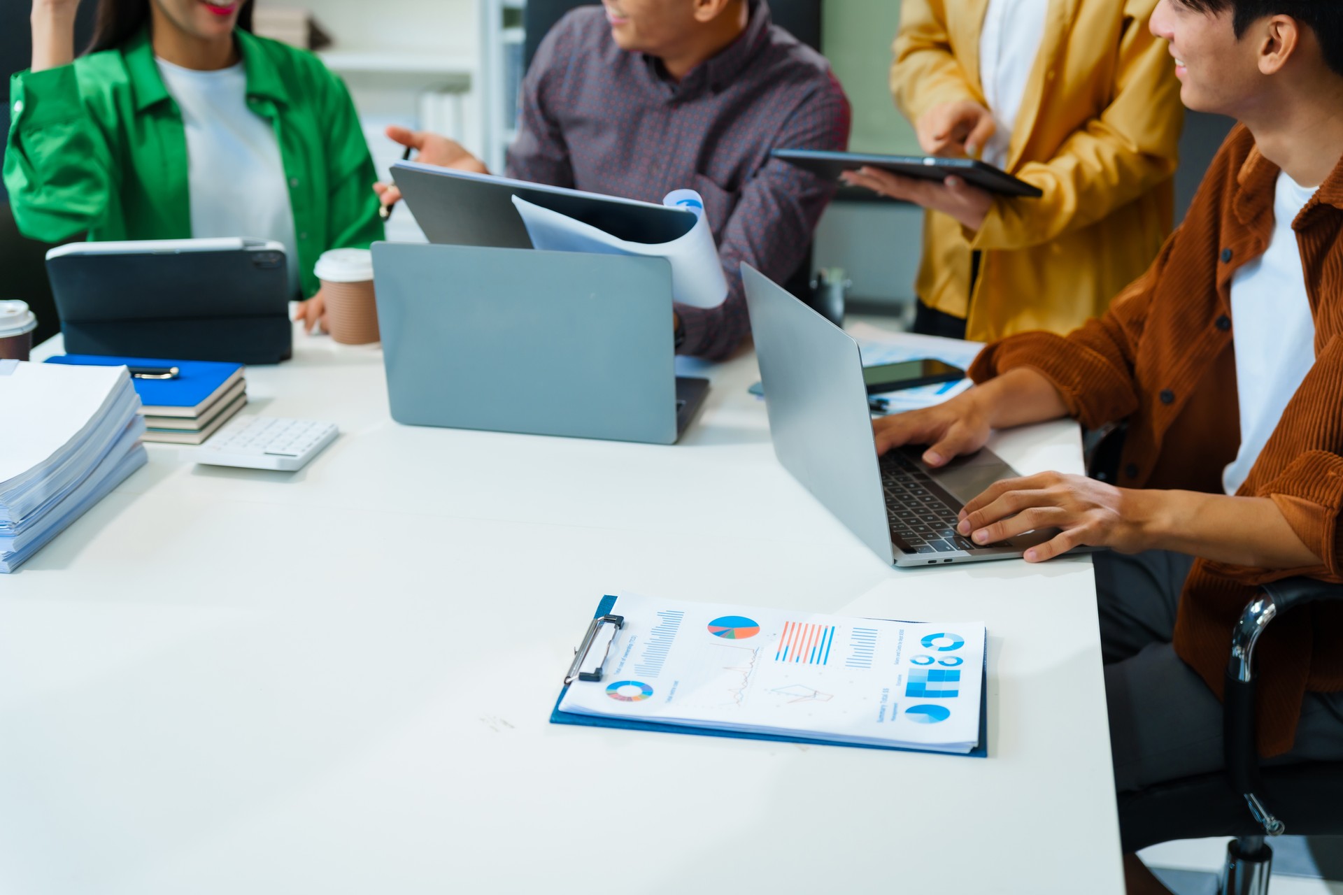 In a boardroom, an Asian team discusses startup financials and business terms. They present strategies on acquisitions, cash flow, and investor relations, innovative approaches for company growth.